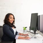 woman in professional wear seated in front of monitor