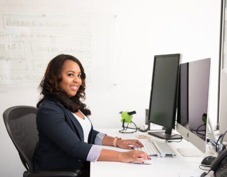 woman in professional wear seated in front of monitor