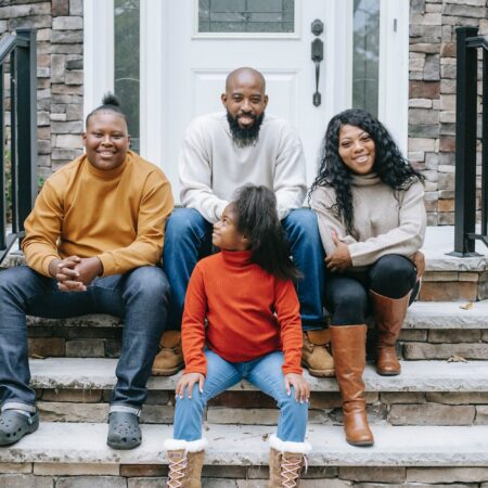 happy black family sitting on stairs of modern house