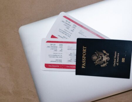 close up shot of a passport and tickets on top of a laptop